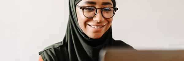 Woman in hijab looking at computer screen smiling