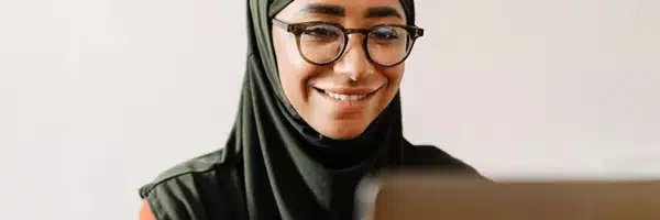 Woman in hijab looking at computer screen smiling