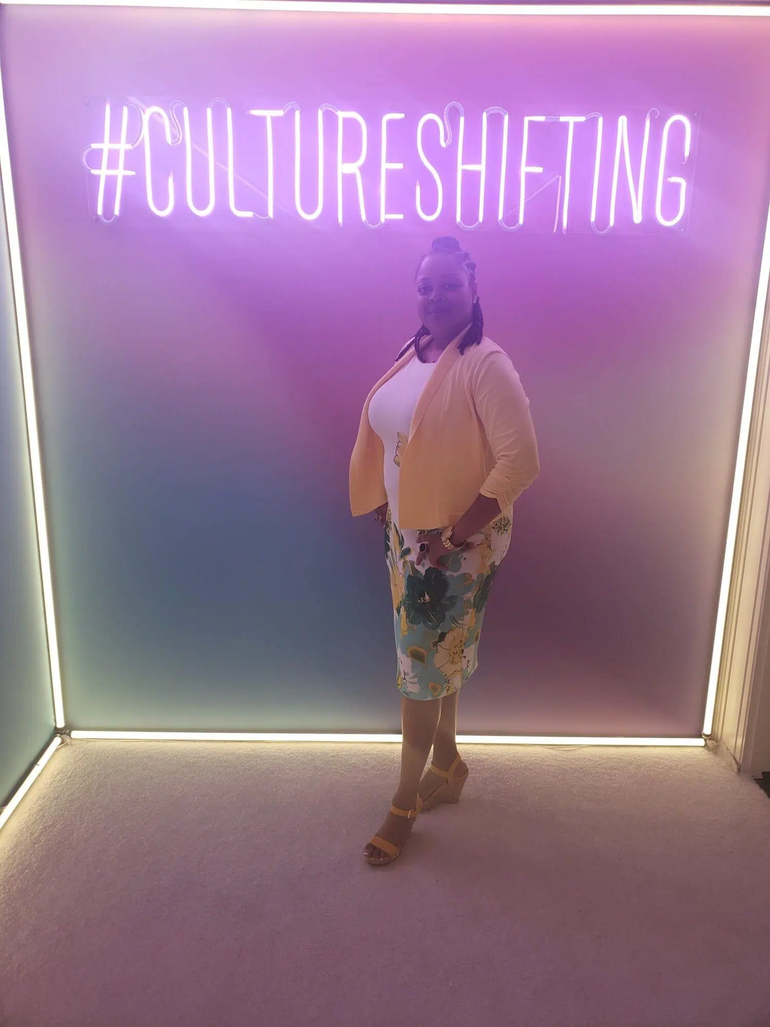 Dominique Hollins in front of a sign that says #cultureshifting